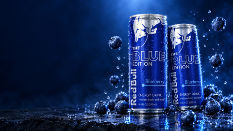 Two Red Bull The Blue Edition blueberry cans surrounded by blueberries