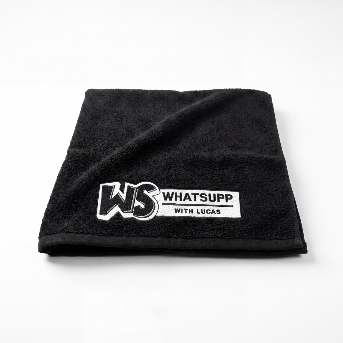 Black Whatsuppwithlucas gym towel folded flat in a square, embroidered WS logo in the corner