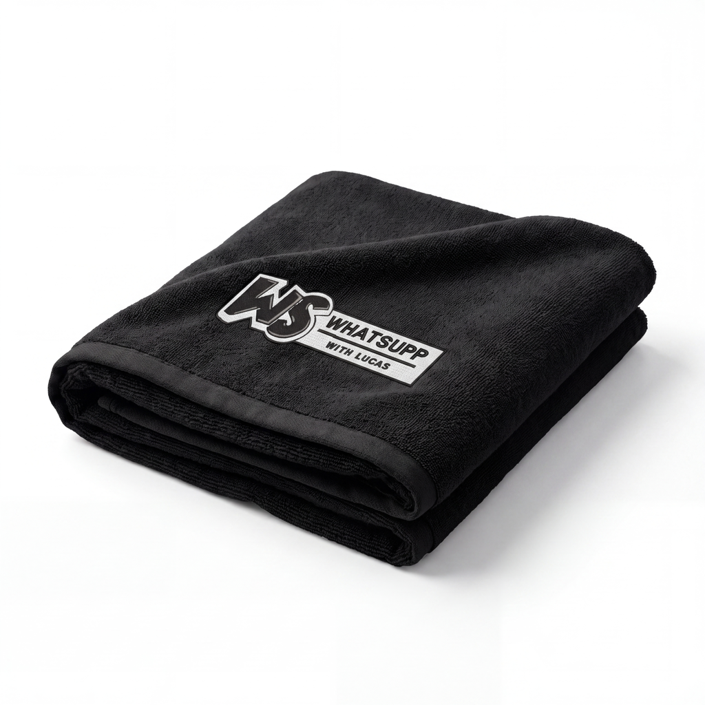 Black Whatsuppwithlucas gym towel folded into a diagonal triangle with the embroidered WS logo